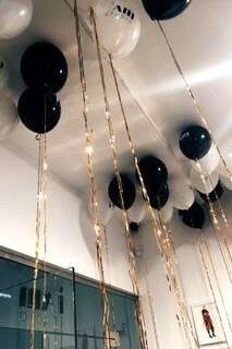 Em preto, branco e dourado, balões são inflados com gás comum, presos no teto com adesivo. Para dar o luxo que a ocasião exige, fitas coloridas iluminadas por led de Natal.
