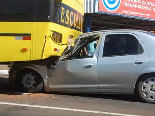 Carro foi parar embaixo da traseira de ônibus escolar na avenida Fábio Zahran. (Foto: Simão Nogueira)
