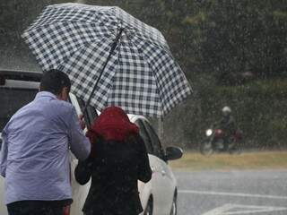 Casal se protege da chuva que teve fortes rajadas de vento nesta quarta-feira (16) na Capital. (Foto: Marcos Ermínio)