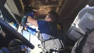Policial rodoviário usa máquina de cortar ferro para retirar tabletes escondidos em compartimento de carreta (Foto: Divulgação/PRF)