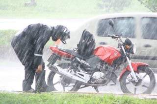 Motociclista teve que parar na rua para se vestir com capa de chuva (Foto: Marcos Ermínio)