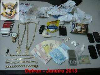 Dinheiro, joias, drogas e outros objetos apreendidos na boca de fumo. (Foto: Divulgação/ Defron)
