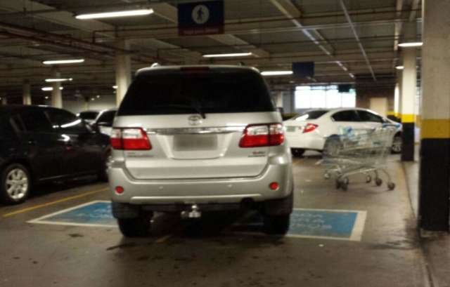 Motorista para em vaga preferencial em estacionamento de supermercado