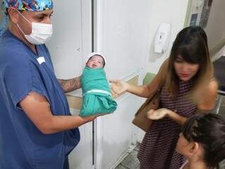 O enfermeiro mostrando Henrique para a avó e irmã. (Foto: Assessoria/Maternidade Cândido Mariano)
