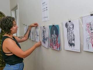A tatuadora Letícia Duarte Ferreira Maidana arrumando o varal com seus desenhos. (Foto: Paulo Francis)