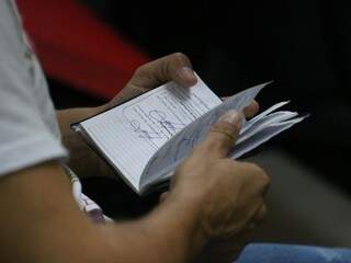 Trabalhador olha anotações na carteira de trabalho enquanto espera atendimento na Funtrab (Foto: Marcos Maluf/Arquivo)