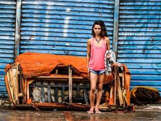 Moradora de rua em frente a um sofá que foi jogado na calçada (Foto: Marcos Maluf)