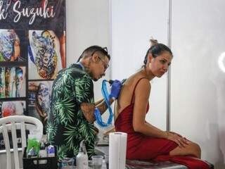 O artista tatuando nas costas da modelo durante o evento. (Foto: Paulo Francis)