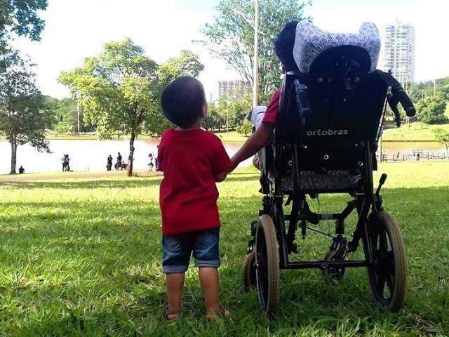Encantados com parque, sobrinho segura a m&atilde;o de tio e juntos observam a natureza
