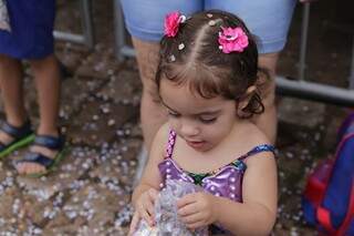 Menina brincando com os confetes carnavalescos. (Foto: Kísie Ainoã)