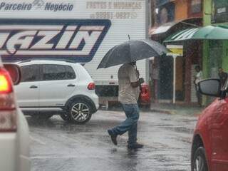 Pedestre estava preparado e abriu guarda-chuva para se proteger de pancada rápida (Foto: Marcos Maluf)