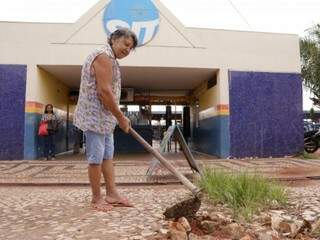 Maria do Carmo Gonçalves carpindo o mato que tem em frente ao Terminal Bandeirantes (Foto: Kísie Ainoã)