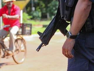 Ciclista passa à frente de policial com armamento pesado, em cidade fronteiriça ao Paraguai. (Fotos: Marcos Maluf)