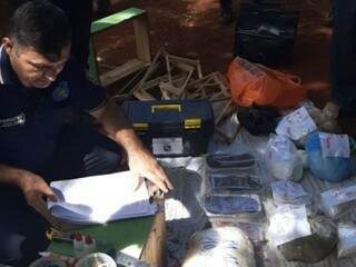 Inspetor próximo a documentos, objetos e droga encontrada na casa (Foto: Divulgação)