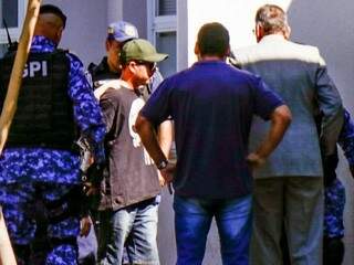 Guarda chegando na delegacia de bermuda, chinelo, camiseta, usando boné e óculos escuros, para não ser identificado pela imprensa (Foto: Henrique Kawaminami) 