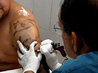 Louiz Otávio Nogueira e Silva fazendo mais uma tatuagem no cliente. (Foto: Alana Portela)