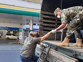 Militar paraguaio ajuda moradora a subir em caminhão usado para transportar pessoas, hoje em Assunção (Foto: Capitán Bado.com)