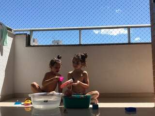 Maria Flor e Maria Luiza lavando os brinquedos na bacia com água. (Foto: Arquivo pessoal)