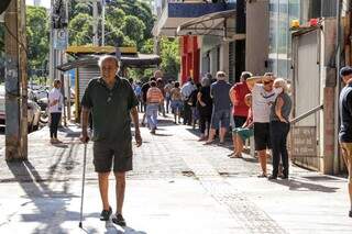 Na fila, de pé ou sentado, no sol ou na somba para conseguir senha na esquina da Afonso Pena com a Rua 14 de Julho (Foto: Kisie Ainoã)