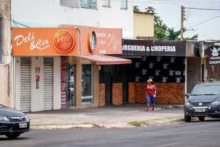 Solitária, mulher passa em frente à lojas fechadas na Rua Ana Luisa de Souza, bairro Pioneiros (Foto: Henrique Kawaminami)