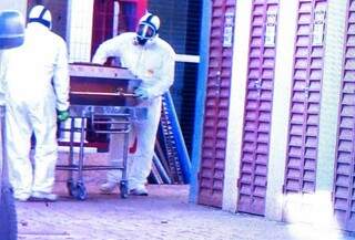 Usando trajes para evitar contaminação, funcionários de funerária carregam caixão com corpo da 1ª vítima do novo coronavírus (Foto: Adilson Domingos)