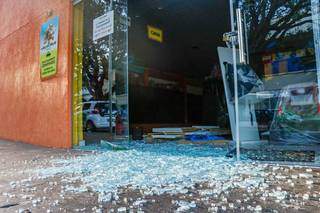 Estilhaços do vidro da porta ficaram espalhados na calçada em frente ao estabelecimento. (Foto: Henrique Kawaminami)