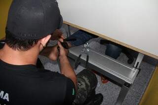 Agente instalando a tornozeleira eletrônica em detento. (Foto: Tatyane Santinoni)