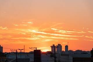 Nascer do sol visto da Avenida Fernando Correia com céu pintado de laranja (Foto: Henrique Kawaminami)