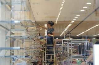 Funcionária de loja no Centro nos últimos preparativos para a reabertura, nesta segunda-feira (06). (Foto: Kisie Ainoã) 