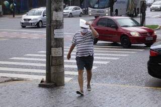 Protegido contra o novo coronavírus, pedestre tenta escapara de chuva no Centro (Foto: Kísie Ainoã)