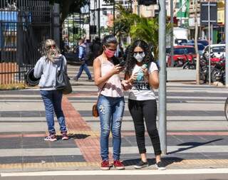 Jovens usam máscaras em canteiro da Avenida Afonso Pena. (Foto: Henrique Kawaminami)