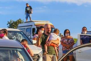 Homem faz oração com criança no colo, ambos desprotegidos, durante evento neste domingo na Avenida Afonso Pena. (Foto: Marcos Maluf)