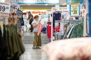 Com máscara, cliente observa roupas em loja do centro de Campo Grande (Foto: Arquivo/Henrique Kawaminami)