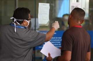 Funcionário de banco usa máscara em fila lotada em agência. (Foto: Marcos Maluf)