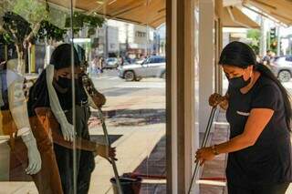Rita Helena limpando a vitrine da loja enquanto conversa com a equipe (Foto: Silas Lima)