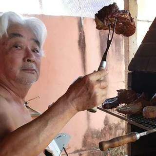 Luiz Mori segurando um pedaço da carne que assou para a família. (Foto: Arquivo pessoal)