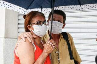 João e Cleonice dividem o guarda-chuva e não abrem mão da máscara; o pedreiro diz ainda ter dúvida sobre os efeitos da mudança de tempo para a pandemia, mas diz que a incerteza só faz aumentar o medo (Foto: Henrique Kawaminami)