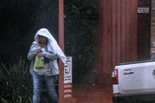 Casaco e toalha na cabeça pra enfrentar a chuva e o frio que chegaram juntos em Campo Grande nesta quarta (6) (Foto: Henrique Kawaminami)