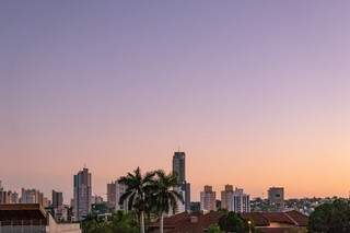 Edifício, árvores e coqueiros compõem cenário do dia amanhecendo no Bairro Itanhanguá Park, na Cidade Morena (Foto: Henrique Kawaminami)