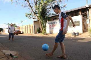 Ricardo chuta bola para o amigo na rua. Ele diz que sente falta da escola (Foto: Kísie Ainoã)