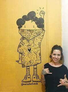 Marina ao lado de um mural que desenhou em uma parede (Foto: Arquivo Pessoal)