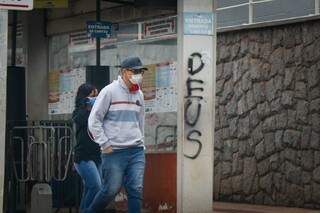 Pedestre se protegendo contra o vírus usando máscara enquanto anda por rua da Capital. (Foto: Henrique Kawaminami) 