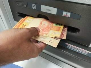 Dinheiro sendo sacado em caixa eletrônico. (Foto: Kisie Ainoã)