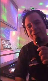 O DJ André usa um microfone para interagir com os seguidores. (Foto: Facebook)