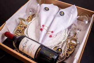 Caixa com vinho, taças, guardanapos de tecido, porta-guardanapos e sousplat. (Foto: Murano Buffet)