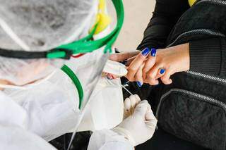 Enfermeira faz teste rápido em terminal de ônibus de Campo Grande. (Foto: Henrique Kawaminami)