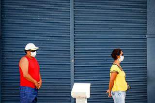 Homem e mulher respeitam distanciamento enquanto aguardam atendimento em fila (Foto: Henrique Kawaminami/Arquivo))