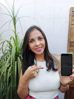 A nutricionista Jéssica Alves apontando para o celular, ferramenta em que grava as lives. (Foto: Arquivo pessoal)