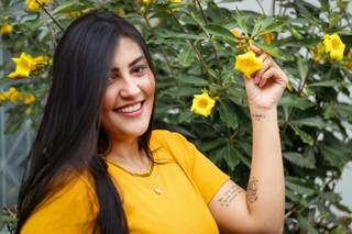 Lorena segurando com flor amarela para combinar com a alegria que traz no peito. (Foto: Henrique Kawaminami)