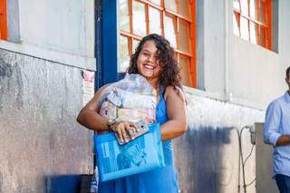 Jheniffer, grávida e mãe de 2, leva os alimentos que vão ajudar no orçamento de casa (Foto: Henrique Kawaminami)